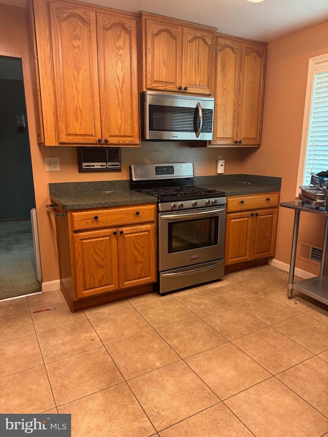 kitchen with appliances with stainless steel finishes, dark countertops, and brown cabinets