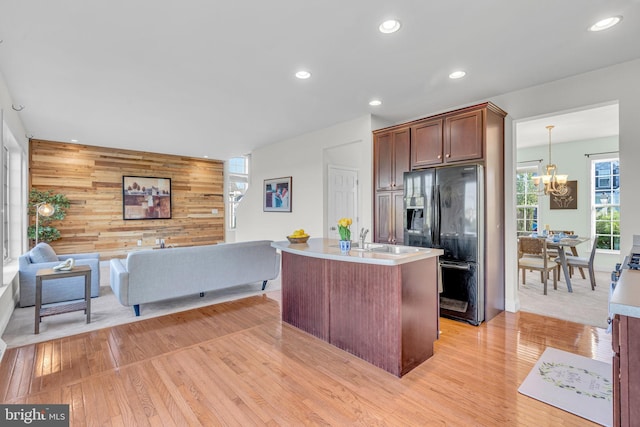 kitchen with an inviting chandelier, black fridge, light wood-style flooring, and open floor plan