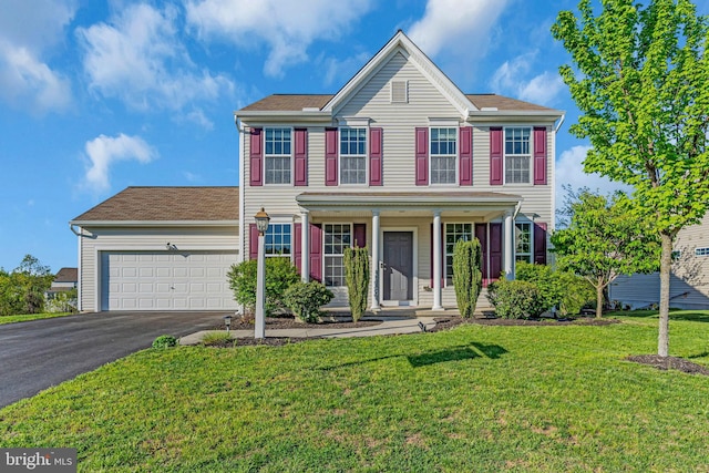 view of front of house with covered porch, an attached garage, driveway, and a front lawn