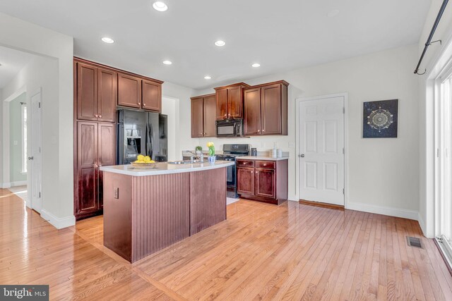 kitchen featuring visible vents, light wood finished floors, baseboards, and black appliances