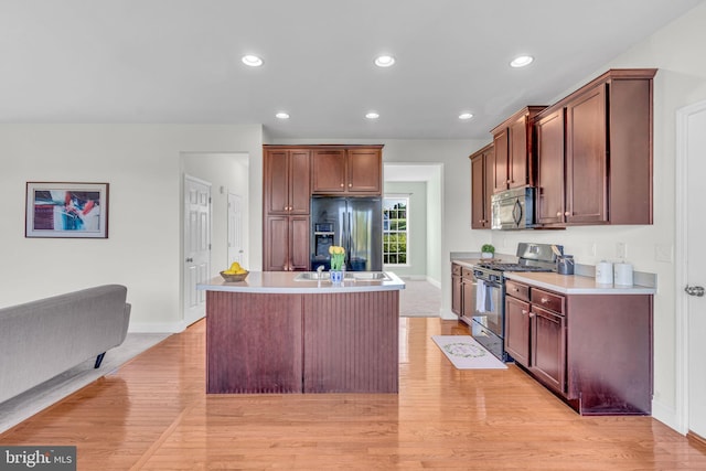 kitchen with baseboards, light wood-style flooring, black fridge, and stainless steel gas range