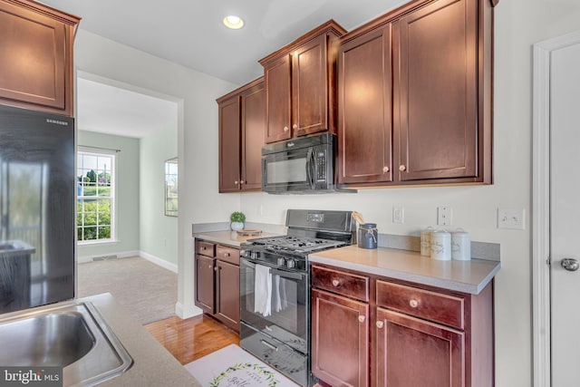 kitchen featuring light wood finished floors, light countertops, recessed lighting, baseboards, and black appliances