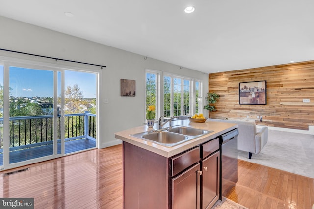 kitchen with wood walls, dishwasher, a sink, light countertops, and recessed lighting