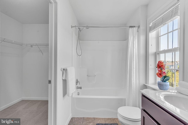 bathroom featuring vanity, toilet, baseboards, shower / tub combo, and a spacious closet