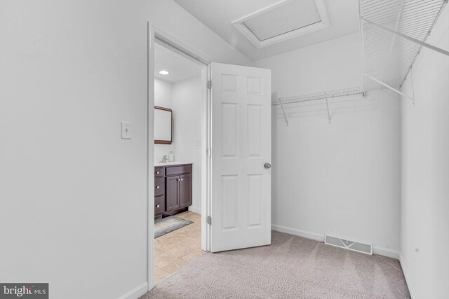 walk in closet featuring light carpet, attic access, and visible vents