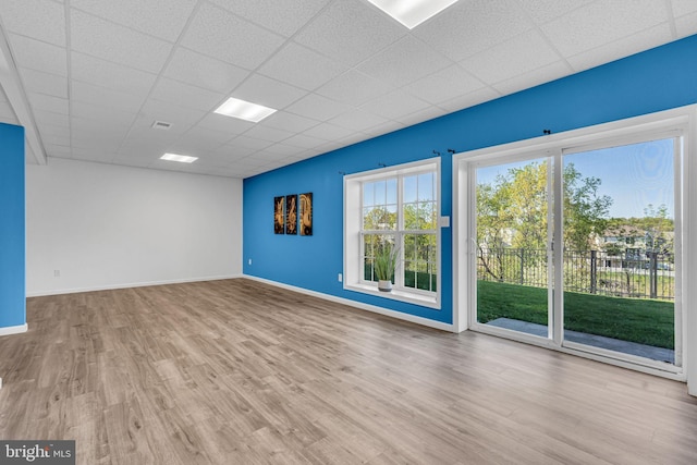 empty room with baseboards, a paneled ceiling, wood finished floors, and visible vents