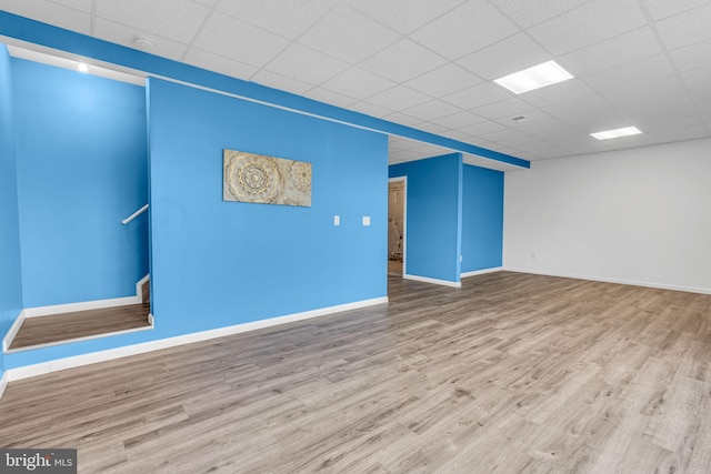 unfurnished room featuring baseboards, a drop ceiling, and wood finished floors