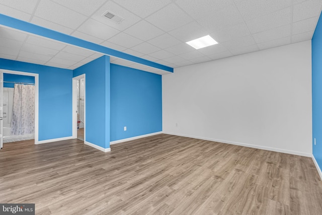 unfurnished room featuring baseboards, a paneled ceiling, and wood finished floors