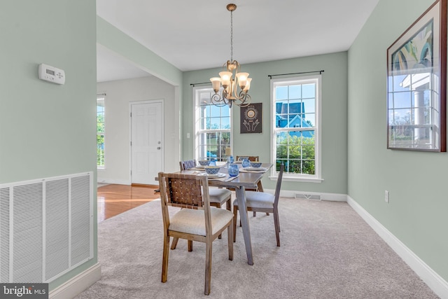 dining area featuring plenty of natural light, light carpet, visible vents, and a notable chandelier
