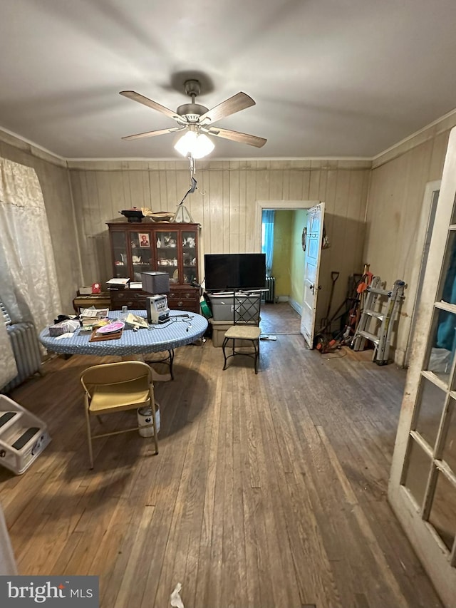 interior space featuring crown molding, a ceiling fan, wooden walls, and hardwood / wood-style flooring