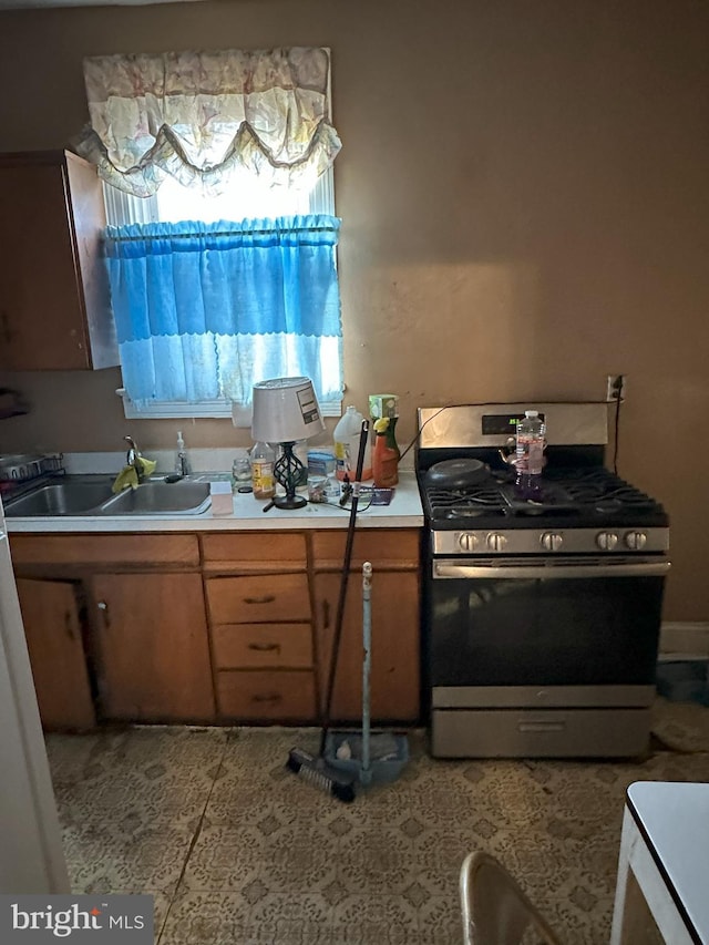 kitchen featuring stainless steel gas range oven, light countertops, plenty of natural light, and a sink