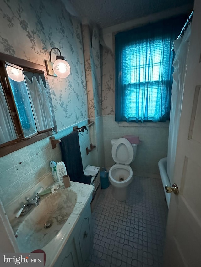 bathroom with tile walls, wallpapered walls, a wainscoted wall, and tile patterned flooring