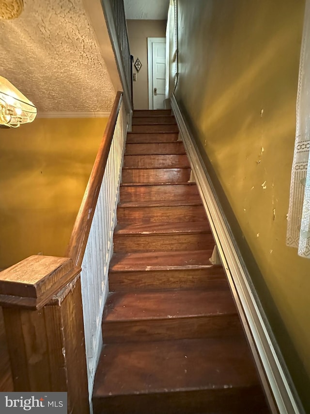 stairway featuring a textured ceiling