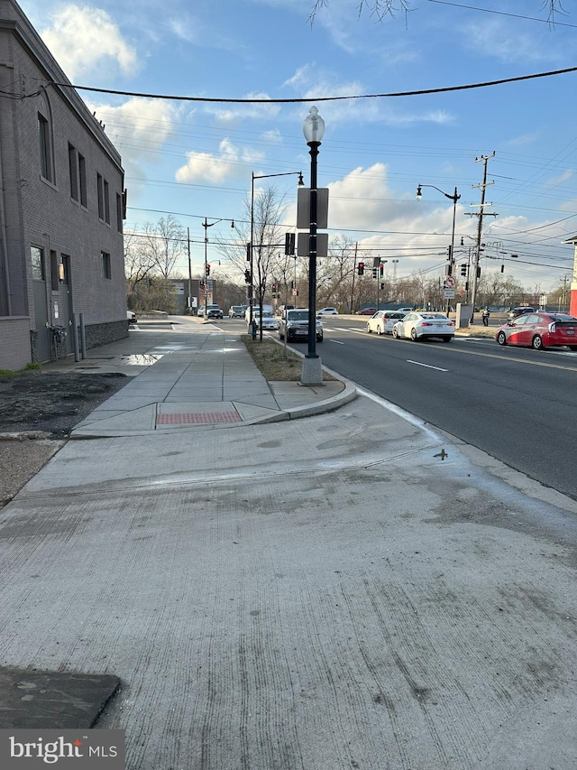 view of street featuring sidewalks, traffic lights, curbs, and street lighting