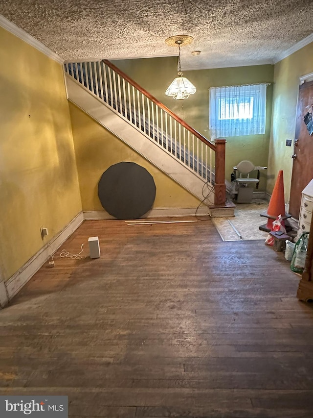 foyer featuring hardwood / wood-style floors, baseboards, stairway, a notable chandelier, and crown molding