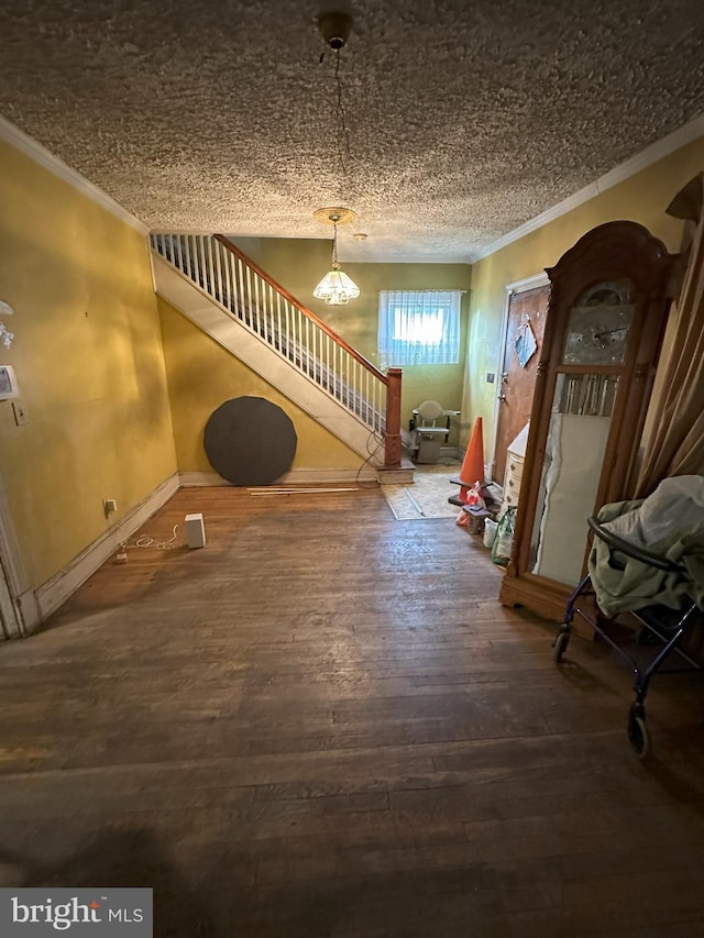entryway with stairs, a chandelier, hardwood / wood-style flooring, baseboards, and crown molding