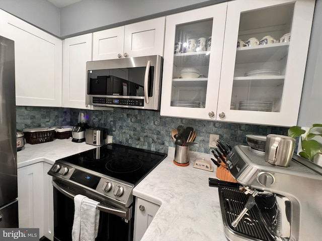 10230 Faire Commons Ct, Burke, VA 22015 - kitchen featuring light stone countertops, glass insert cabinets, white cabinetry, appliances with stainless steel finishes, and backsplash