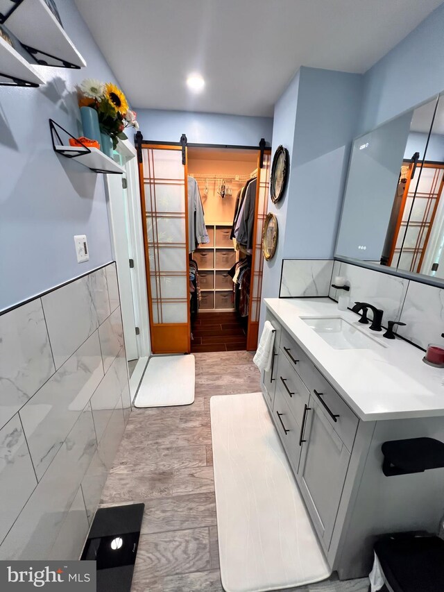 10230 Faire Commons Ct, Burke, VA 22015 - bathroom featuring vanity, wood finished floors, a spacious closet, and tile walls