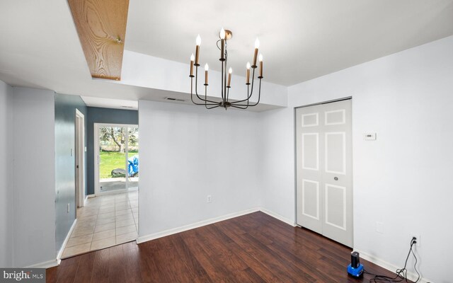 unfurnished dining area featuring a chandelier, visible vents, wood finished floors, and baseboards