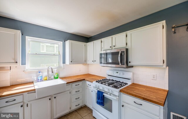 kitchen featuring stainless steel microwave, white cabinetry, white range with gas stovetop, butcher block countertops, and backsplash