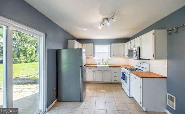 kitchen featuring tasteful backsplash, visible vents, wooden counters, stainless steel appliances, and light tile patterned flooring