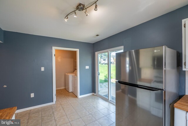 kitchen featuring light tile patterned floors, visible vents, freestanding refrigerator, baseboards, and separate washer and dryer