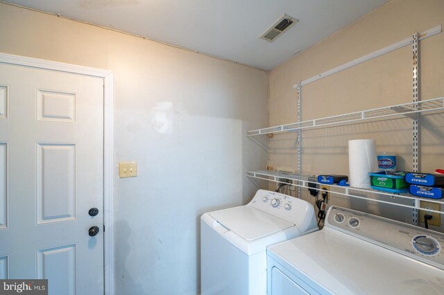 washroom featuring visible vents, washing machine and clothes dryer, and laundry area