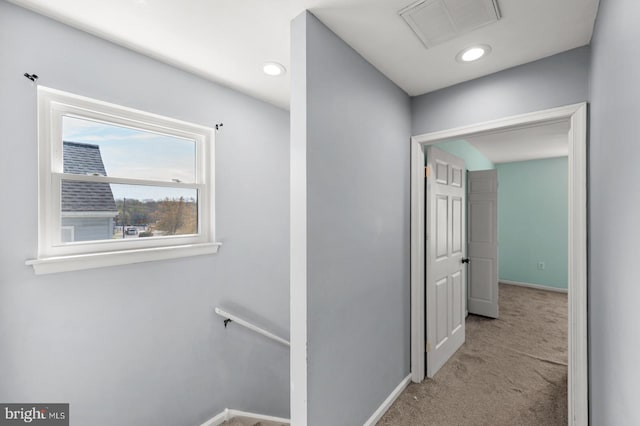hall featuring an upstairs landing, visible vents, carpet, and baseboards