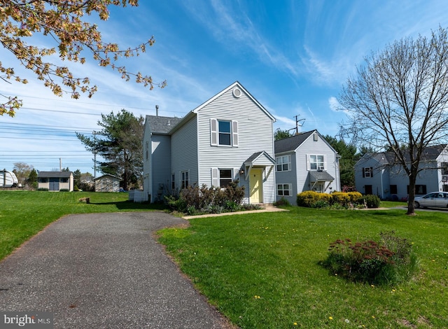 traditional-style house with aphalt driveway and a front yard