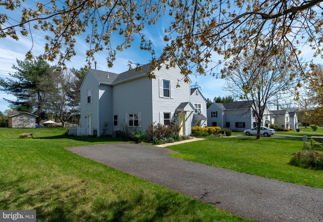 view of side of home featuring a lawn and aphalt driveway