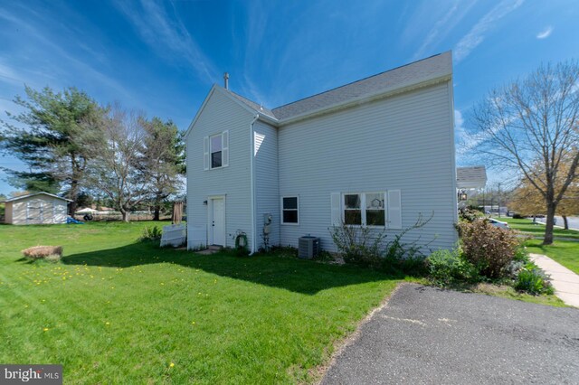 view of side of property with a lawn and central air condition unit