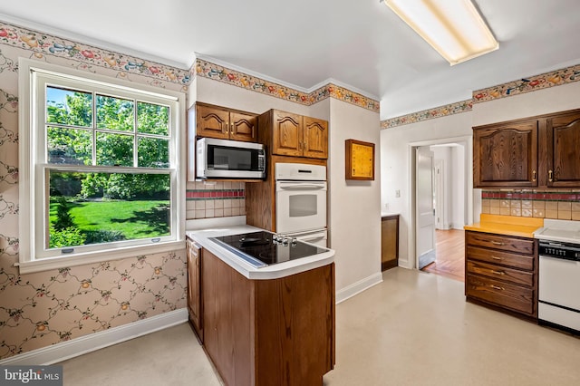 kitchen featuring a healthy amount of sunlight, light countertops, stainless steel microwave, and black electric stovetop