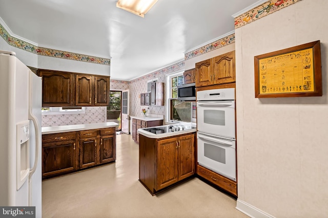 kitchen featuring light countertops, a peninsula, white appliances, and wallpapered walls