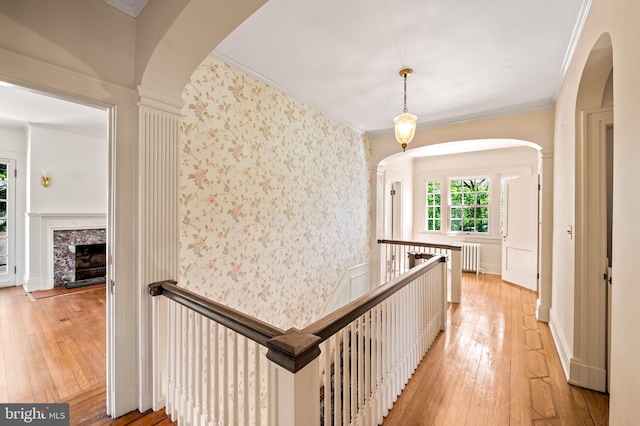 hall with radiator, ornamental molding, and light wood finished floors