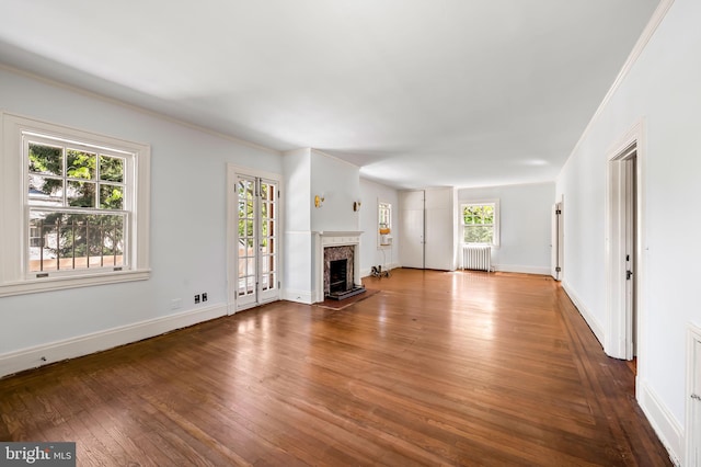 unfurnished living room featuring baseboards, radiator heating unit, a premium fireplace, and hardwood / wood-style flooring
