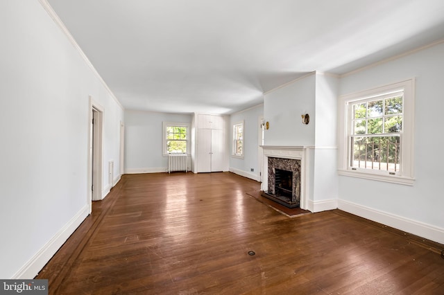 unfurnished living room featuring crown molding, dark wood-style flooring, baseboards, radiator heating unit, and a high end fireplace