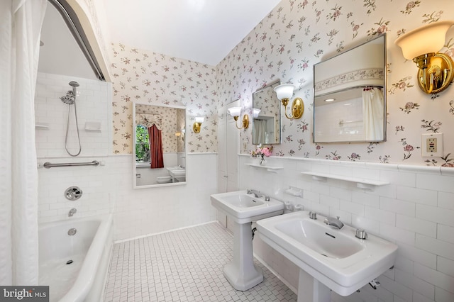 full bath with wallpapered walls, wainscoting, two sinks, and tile patterned floors