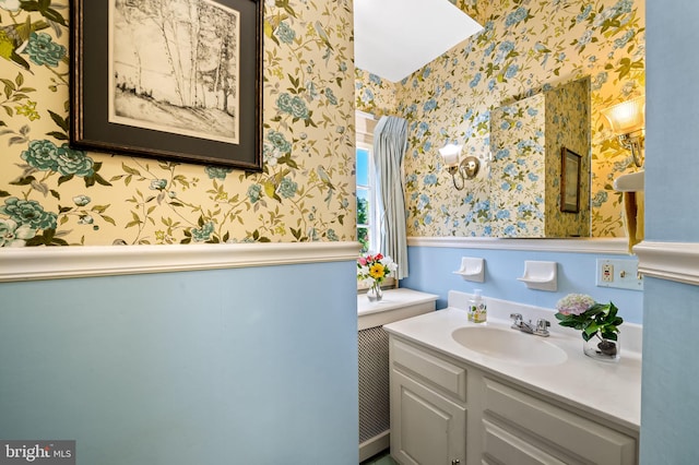 bathroom featuring a wainscoted wall, vanity, and wallpapered walls