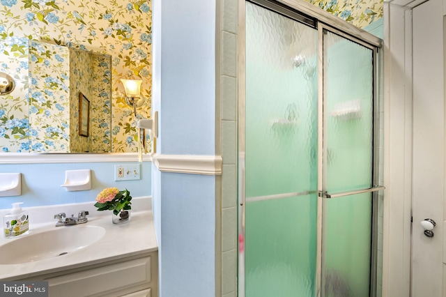 bathroom featuring vanity, a shower stall, and wallpapered walls
