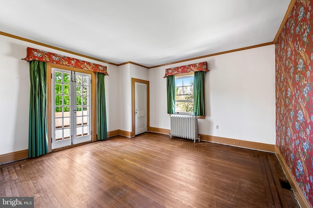 empty room featuring crown molding, radiator heating unit, a wealth of natural light, and hardwood / wood-style floors