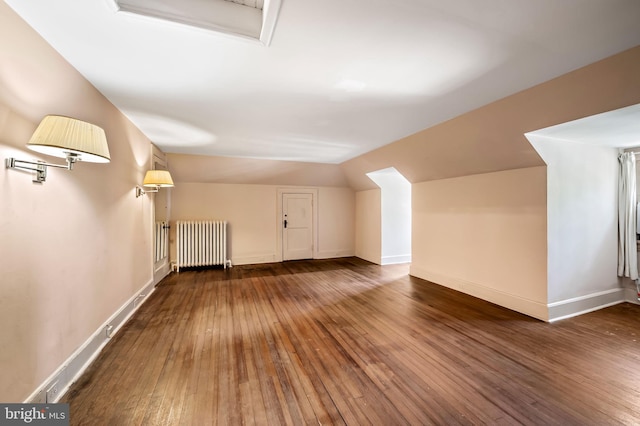 bonus room with radiator heating unit, baseboards, wood-type flooring, and vaulted ceiling