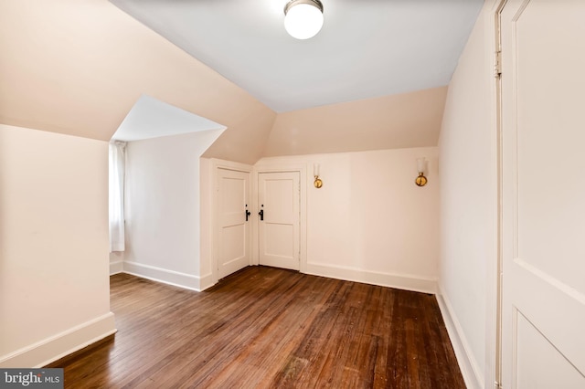 additional living space featuring baseboards, lofted ceiling, and hardwood / wood-style flooring