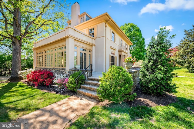 exterior space featuring french doors, stucco siding, a yard, and a chimney