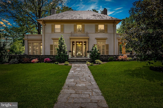 view of front facade featuring a chimney, a front lawn, and stucco siding