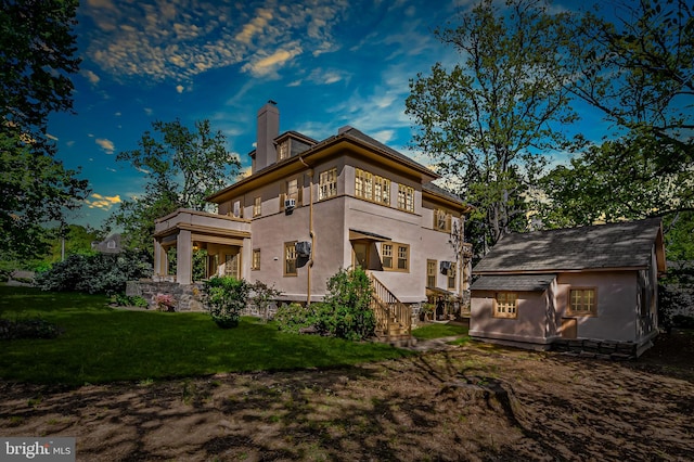 rear view of property with a lawn, stucco siding, a balcony, and a chimney