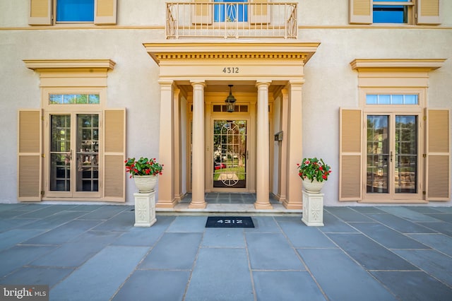 view of exterior entry featuring stucco siding and a balcony