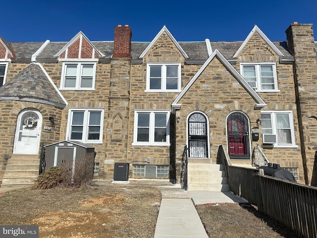 view of front of house featuring a chimney, central air condition unit, and stone siding