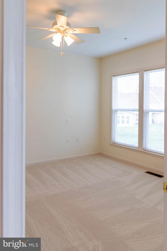 empty room featuring ceiling fan, light carpet, and baseboards