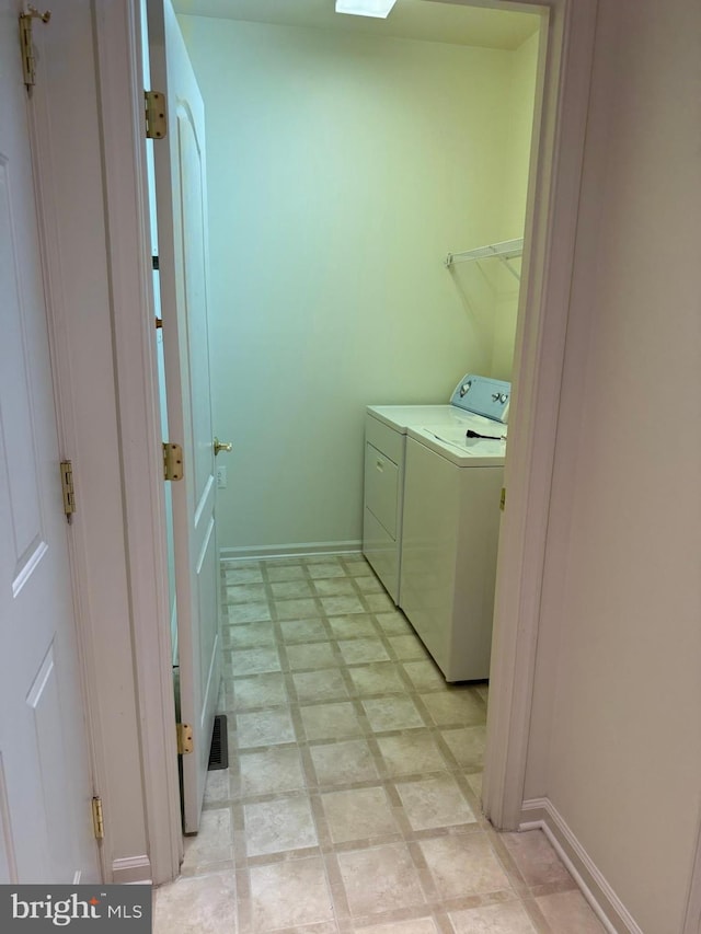 laundry room with light floors, washer and dryer, laundry area, and baseboards