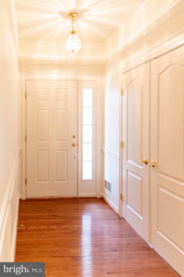 entrance foyer with visible vents, a decorative wall, and light wood-type flooring